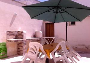 a table and chairs with a green umbrella at Casa Giovanni by My Home Apulia in Torre Lapillo