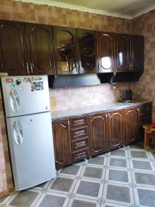 Guesthouse Irina Family Hotel في Tsvirmi: مطبخ مع ثلاجة بيضاء ودواليب خشبية