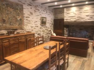 uma sala de jantar com uma mesa de madeira e uma parede de pedra em Gite équestre du Dourdu em Lopérec