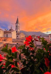 una vista de una iglesia con flores rojas en el primer plano en Regina d’Aragona casa vacanze, en Sulmona