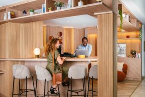 a man and a woman standing at a bar in a kitchen at Aparthotel Adagio Paris Opéra in Paris