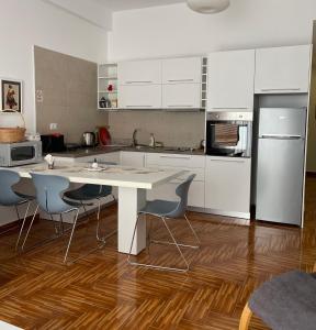 a kitchen with white cabinets and a table and chairs at Port Side Sarande in Sarandë