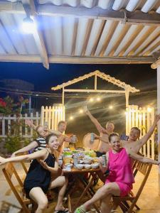 a group of people sitting around a table with their arms up at phòng mùa thu in Tuy Hoa