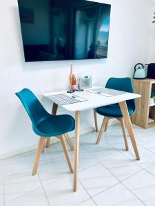 エンプリアブラバにあるFace a la Mer - vue epique, climatisation, wifi, draps inclusの白いテーブルと青い椅子2脚