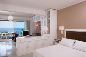 Schlafzimmer mit einem Bett und einem Schreibtisch mit einem TV in der Unterkunft Studio in Villa Oasis Residence in Taormina in Mazzeo