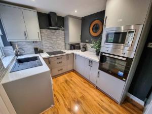 a kitchen with white appliances and wooden floors at 3 BR Home Close to MCR City Centre in Manchester