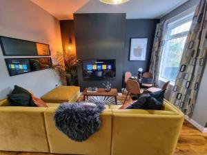 a living room with a yellow couch with pillows at 3 BR Home Close to MCR City Centre in Manchester