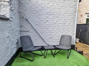 duas cadeiras sentadas em frente a uma parede de tijolos em 3 BR Home Close to MCR City Centre em Manchester
