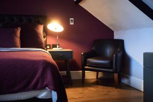um quarto com uma cama, uma cadeira e um candeeiro em The Brown's Hotel em Laugharne