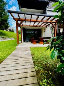 a wooden pathway leading to a house with a wooden pergola at Relax in nature Apartment in Bovec