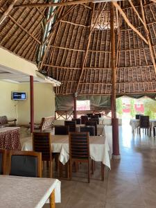 restauracja ze stołami i krzesłami oraz słomianym dachem w obiekcie Lake Jipe Eco Lodge w mieście Tsavo West National Park