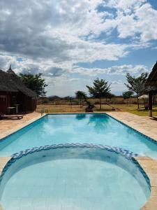 a large swimming pool with a field in the background at Lake Jipe Eco Lodge in Tsavo West National Park