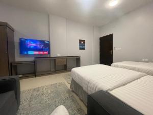 a hotel room with two beds and a flat screen tv at LOTA Suites in Al Baha