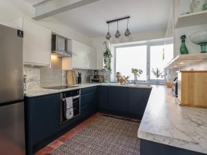 a kitchen with blue cabinets and a large window at Windycroft in Barmouth