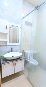 een witte badkamer met een wastafel en een spiegel bij Love Hotel & Apartments in Vung Tau