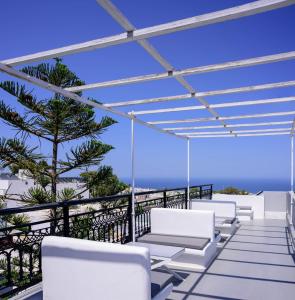 una fila de sillas blancas en un balcón con vistas al océano en Fira Vista Hotel, en Fira