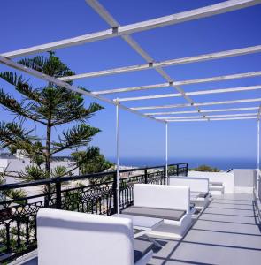 a row of white chairs on a balcony with the ocean at Fira Vista Hotel in Fira