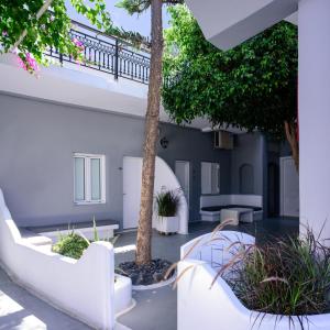 a courtyard with white furniture and a palm tree at Fira Vista Hotel in Fira