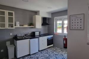 a small kitchen with white cabinets and a sink at Casa da Praça 2 in São João da Madeira