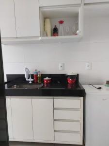 a white kitchen with a sink and a counter at Apartamento luxo no centro in Ubá