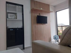 een woonkamer met een bank en een tv aan de muur bij Apartamento luxo no centro in Ubá