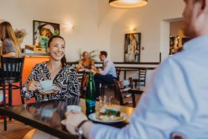 een vrouw aan een tafel met een bord eten bij Hotel Merkur - Czech Leading Hotels in Praag