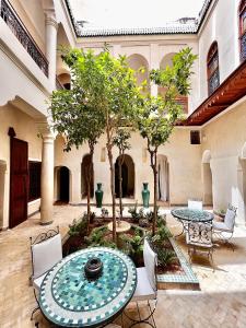 einen Innenhof mit einem Tisch, Stühlen und Bäumen in der Unterkunft Riad Dar Zaouia in Marrakesch