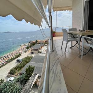 a balcony with a view of a beach and an umbrella at Port Side Sarande in Sarandë