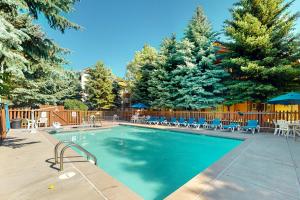 a swimming pool with tables and chairs and trees at Crazy Horse Hideaway in Edwards