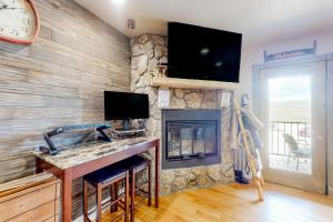 a living room with a fireplace and a flat screen tv at Charming Pad in Granby