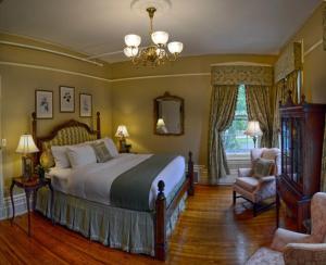 a bedroom with a bed and a chair and a chandelier at Maxwell Mansion Hotel in Lake Geneva