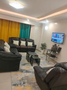 a living room with leather furniture and a flat screen tv at Executive 3 bedroom in Nakuru CBD in Nakuru