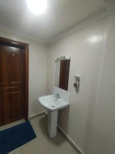 a bathroom with a white sink and a wooden door at Executive 3 bedroom in Nakuru CBD in Nakuru