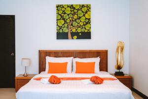a bedroom with a bed with orange pillows and a painting at Layantara Resort, Phuket in Layan Beach