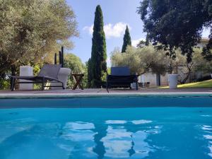 - une piscine avec 2 chaises, une table et des arbres dans l'établissement Bastide Castella, à Montpellier