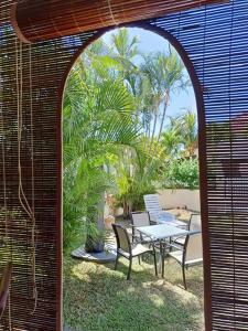 a patio with a table and chairs and palm trees at KASPOZ Entire Holiday Home - Private garden & 5 mins walk to the beach in Mont Choisy