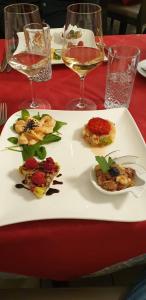 a plate of food on a table with glasses of wine at Hotel Ristorante Camoghe in Isone