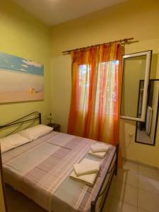 - une chambre avec un lit doté d'un rideau orange et d'une fenêtre dans l'établissement VILLA ANNA, à Ravdhoúkha