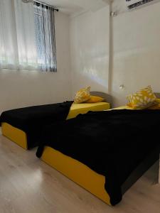 two beds with black and yellow sheets in a room at ANKA APARTMENT in Štip