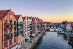 a group of buildings next to a river with boats at Deo Plaza Old Town Gdańsk - Praia Apartaments in Gdańsk