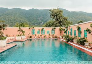 a swimming pool in front of a building with mountains in the background at HOTEL WHITE RABBIT in Pushkar