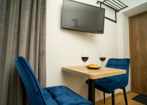 een kamer met een tafel en twee blauwe stoelen en een tv bij Fort63 house in Kaunas