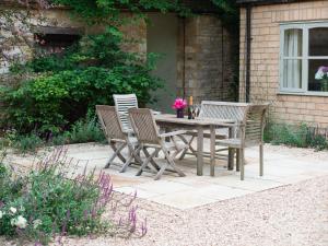 a wooden table and chairs with flowers on a patio at Woodland Cottage in Temple Guiting