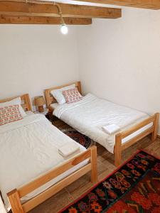 two twin beds in a room with a rug at Bobića konak - Lukomir in Lukomir