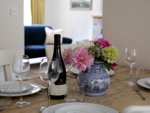a table with a bottle of wine and a vase of flowers at Woodland Cottage in Temple Guiting
