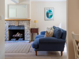 a blue couch in a living room with a fireplace at Woodland Cottage in Temple Guiting