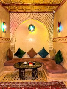 a room with a bench with a table and a clock at RIAD AMNAY in Taroudant
