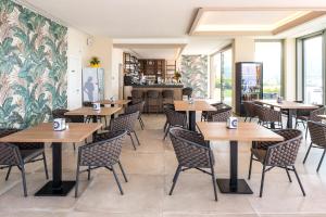 un restaurante con mesas y sillas de madera y un bar en Hotel Du Parc, en Garda