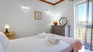 a white bedroom with a bed and a window at Casa Mia by LovelyStay in Lagoa