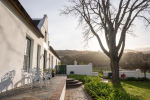 a patio with white chairs and a tree at Laborie Jonkershuis in Paarl